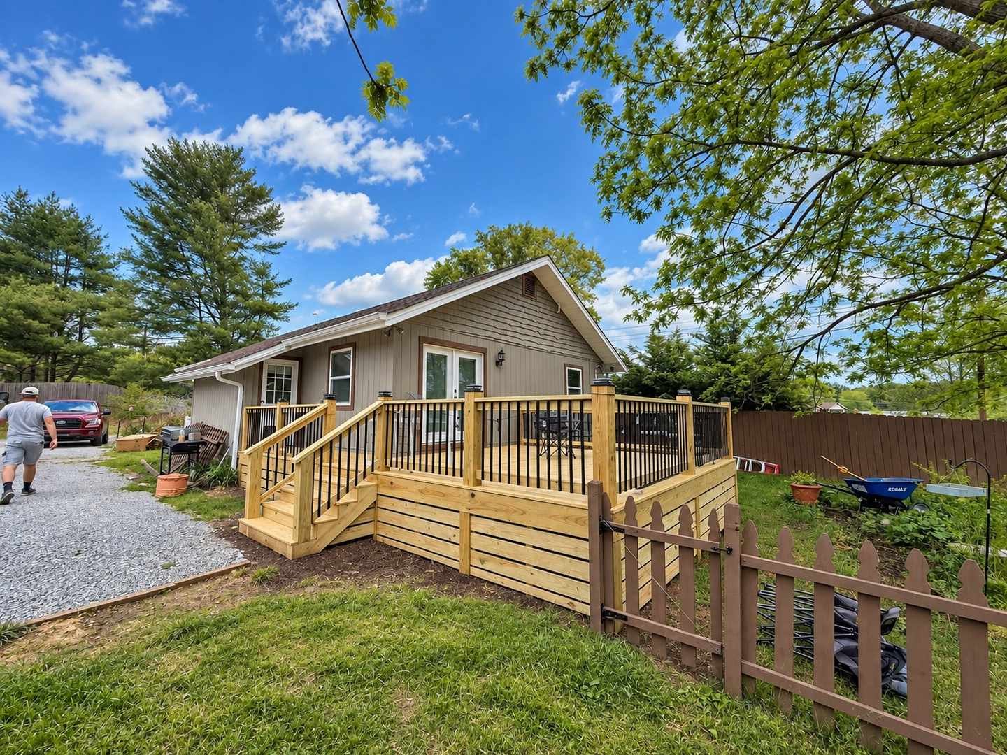 Finished pressure-treated deck with black metal balusters, skirting, and stairs off the back of a ranch home