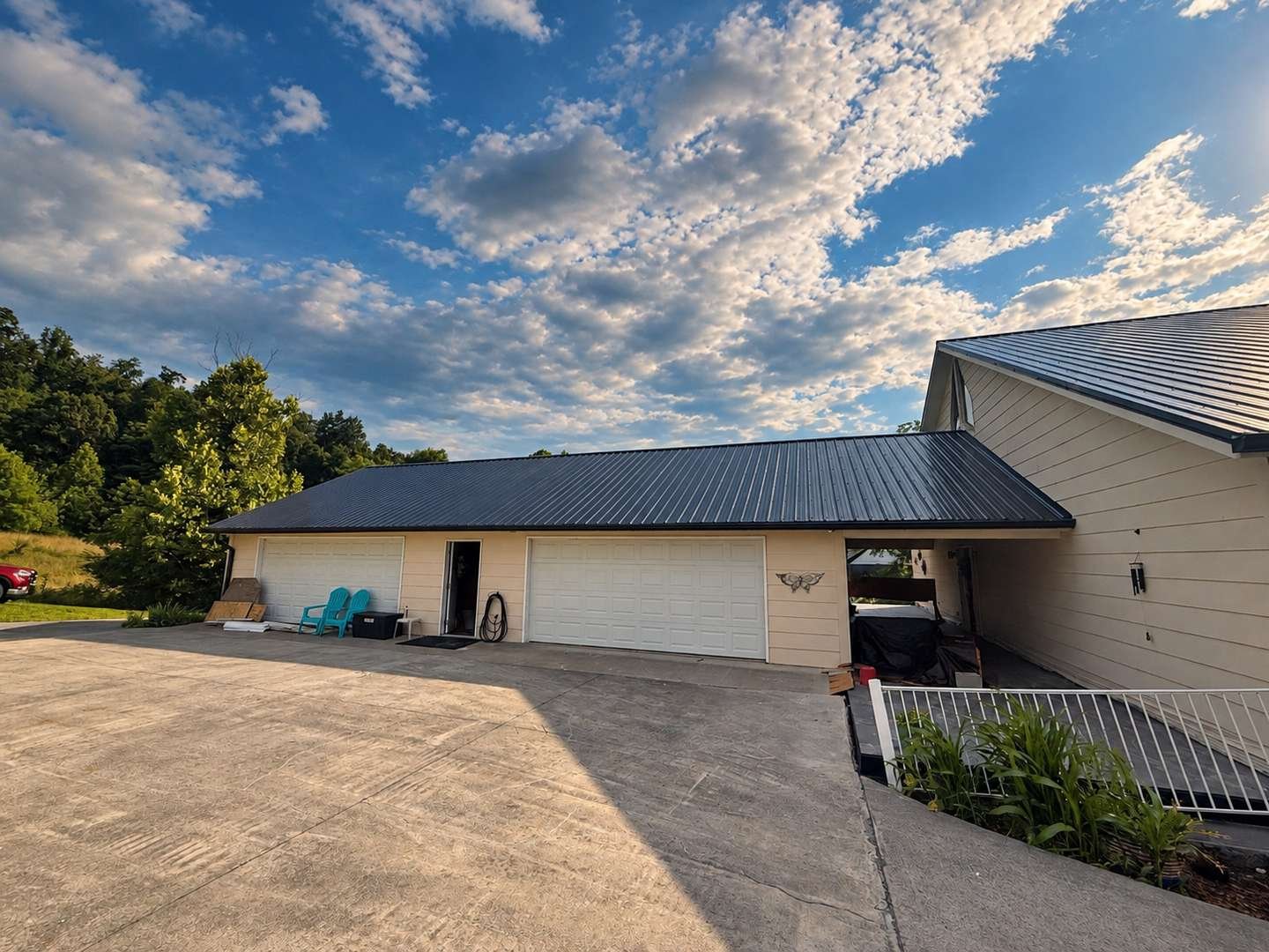 Black Tuff-Rib metal roof over a cream garage and attached home under a bright sky
