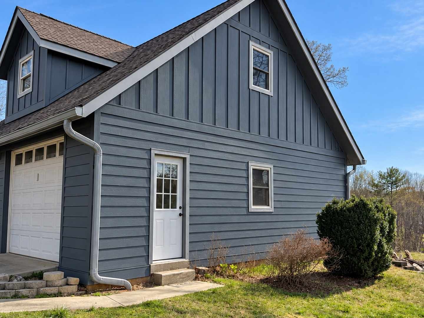 Finished blue-grey siding on a home, with horizontal lap siding, a board-and-batten gable, and white trim